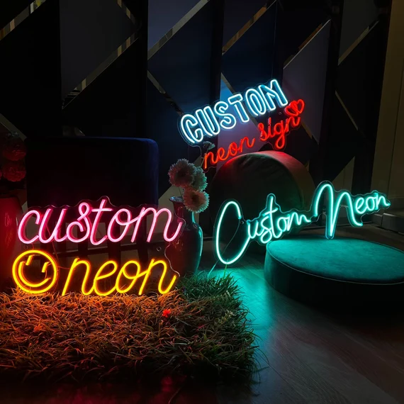 A neon sign spelling "CUSTOM neon sign" in multiple colors, mounted on a plain illuminated wall over a sofa/bench.